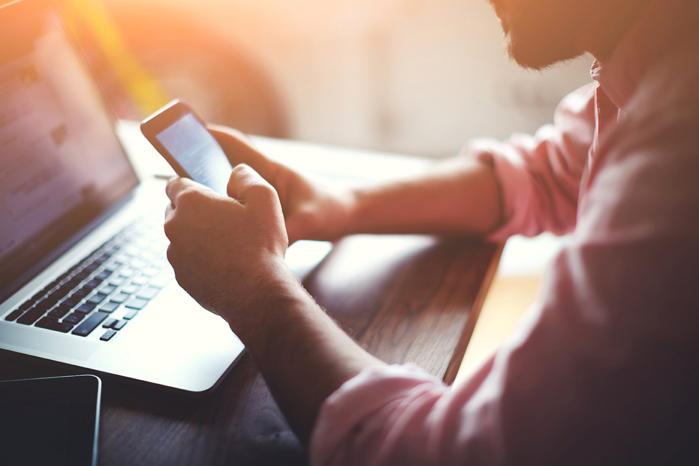 Man looking at phone and laptop